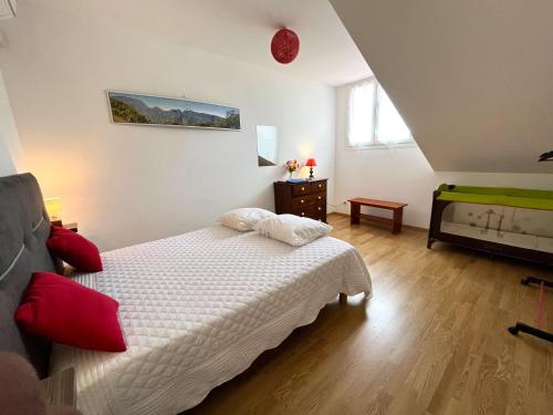 a bedroom with a white bed with red pillows at Le Quindio in Bras-Panon