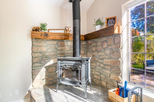 a stone fireplace in a living room with a stove at Mystic Mountain Villa, 14 miles from Yosemite in Oakhurst