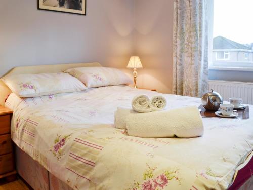 a bedroom with a bed and a table and a window at Frankcot in Llandudno