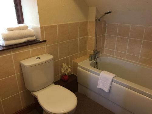 a bathroom with a toilet and a tub with towels at Master Mustard in Hartoft End