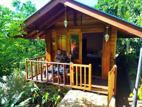 a man and woman sitting on the porch of a wooden cabin at Diyaluma View Cotage in Koslanda