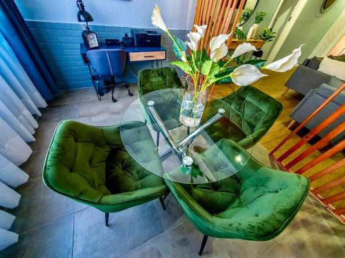a glass table with green chairs and a vase of flowers at Mdumela Stays 2 Bedroom Modern City Apartment in Pietermaritzburg