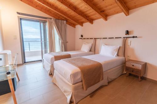 two beds in a room with a large window at Sofita με θέα τη θάλασσα Villa Athina in Preveza