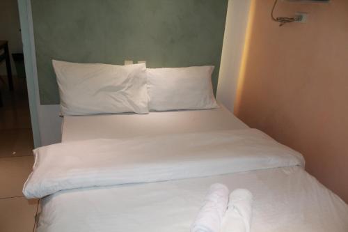 a bed with white sheets and white pillows at Premiere Haven MOA Staycation in Manila