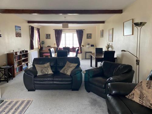 a living room with two leather couches and a table at Spacious family & dog friendly home from home with sea views and private garden in Porlock