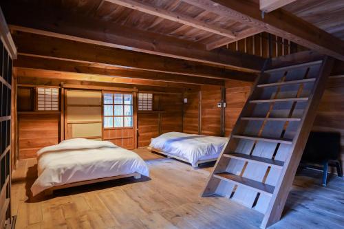 2 camas en una habitación con paredes de madera en 古民家オーベルジュmocca, en Kokuryō