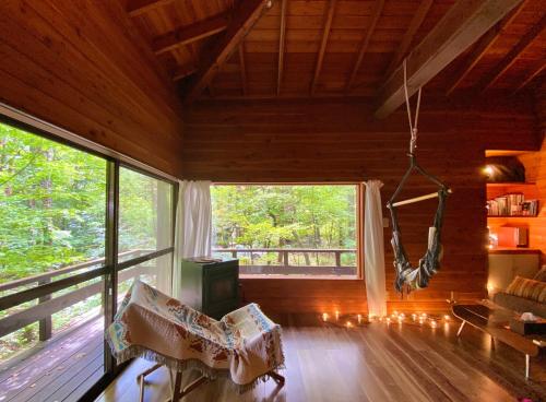 a living room with a large window and a swing at KOMOREBI House -北軽井沢 木漏れ日の家- ペット可 in Kita-karuizawa