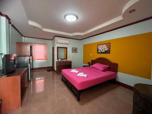 a bedroom with a pink bed and a television at Seven-in in Ban Khlong Chi Lat