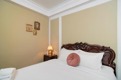 a bedroom with a white bed with a wooden headboard at SAZI BEN THANH Hotel HCM in Ho Chi Minh City
