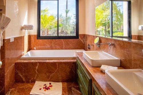 La salle de bains est pourvue de 2 lavabos, d'une baignoire et de fenêtres. dans l'établissement Villa marrakech, à Marrakech