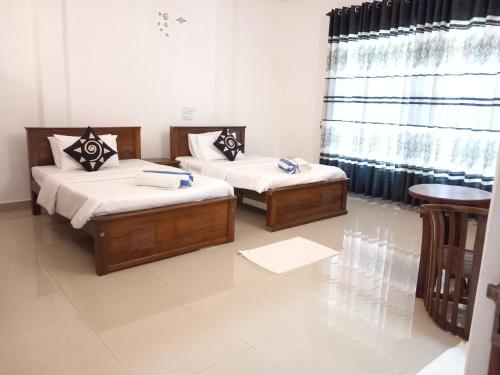 Habitación con 2 camas, mesa y ventana en Senu Beach villa en Alutgama