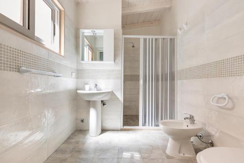 bagno bianco con lavandino e servizi igienici di Casa Jonica by BarbarHouse a San Pietro in Bevagna