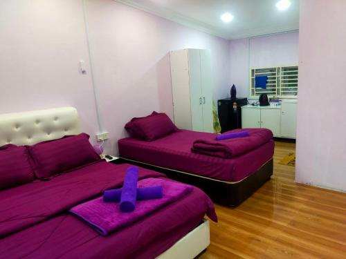 a bedroom with two beds with purple sheets and purple pillows at AR HOMESTAY & ROOMESTAY in Merlimau