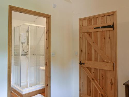 a bathroom with a wooden door and a shower at Swallows Loft in Cromford