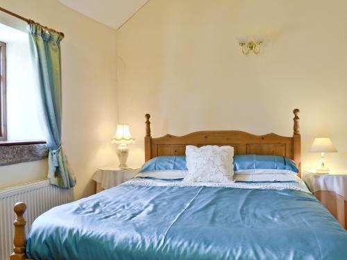 a bedroom with a bed with blue sheets and a window at Swallows Loft in Cromford