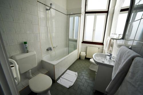 a bathroom with a tub and a toilet and a sink at Hotel Pannonia in Miskolc