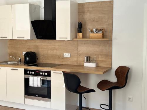 a kitchen with white cabinets and a counter with stools at M96 Ferienwohnung in Seßlach