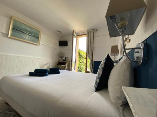 a bedroom with a large white bed with blue pillows at Hôtel Bien-Être Aux Cyprès de Marquay in Marquay