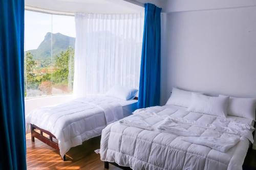 two beds in a bedroom with a large window at Span Grand @ Nuwara Eliya in Nuwara Eliya