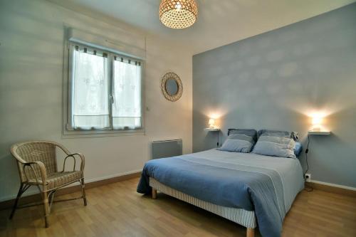 a bedroom with a blue bed and a chair at La Maison aux Volets Roses in Saint-Alban