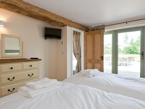 a bedroom with two beds and a dresser with a mirror at Eastlands Barn in East Barkwith