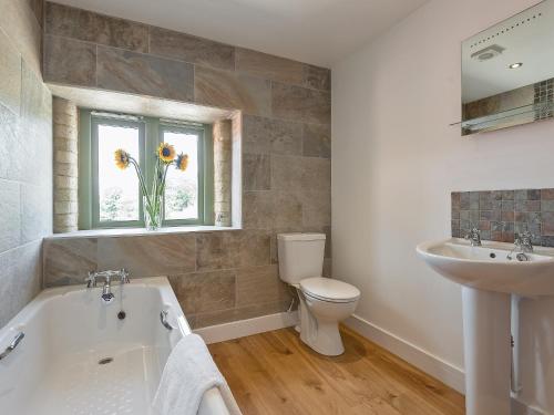 uma casa de banho com uma banheira, um lavatório e um WC. em Eastlands Barn em East Barkwith