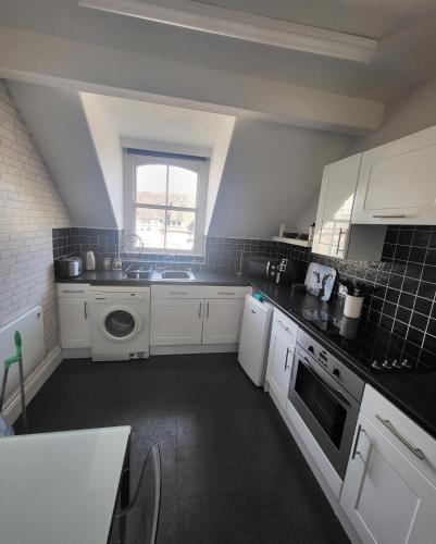 a small kitchen with white cabinets and a window at Willesden, Flat 2, A 1 Bedroom flat right in the heart of Llandudno in Llandudno