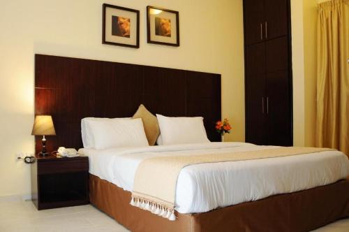 1 dormitorio con 1 cama grande y cabecero de madera en New Royal Palace Hotel Apartments en Ajman 