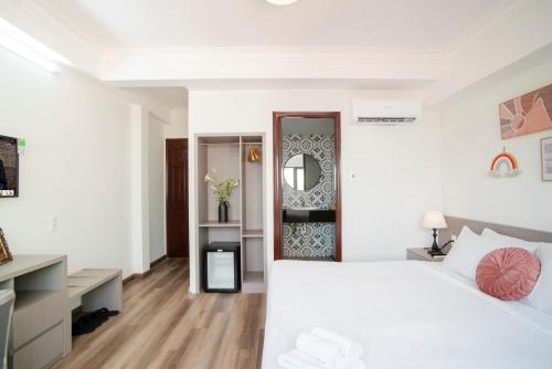 a white bedroom with a large bed and a mirror at SAZI BEN THANH Hotel HCM in Ho Chi Minh City