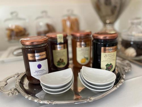 a tray with three jars of jam and plates on a counter at Duchessa Margherita Chateaux & Hotels in Vicoforte