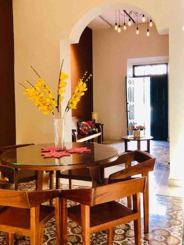 a dining room table with chairs and a vase with flowers at Casa Valentina: lovely house in downtown Merida in Mérida