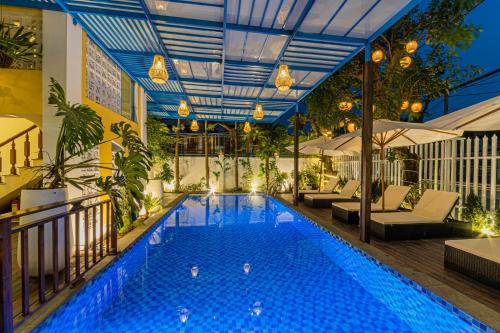 a pool in a hotel with chairs and a table at Hoi An Heart hostel Villa - Bespoke in Hoi An