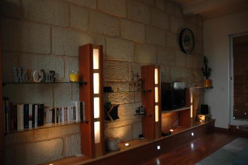 a room with bookshelves and a tv on a stone wall at L'Appel de la Loire in Saumur