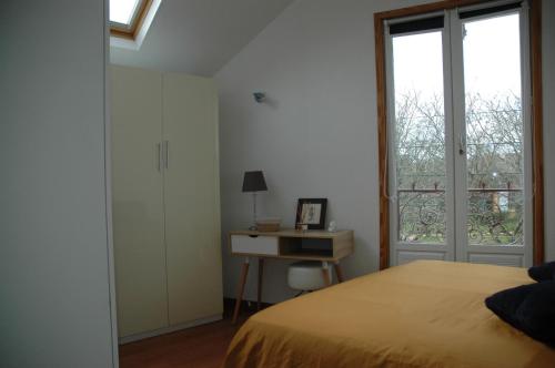 um quarto com uma cama, uma secretária e uma janela em L'Appel de la Loire em Saumur