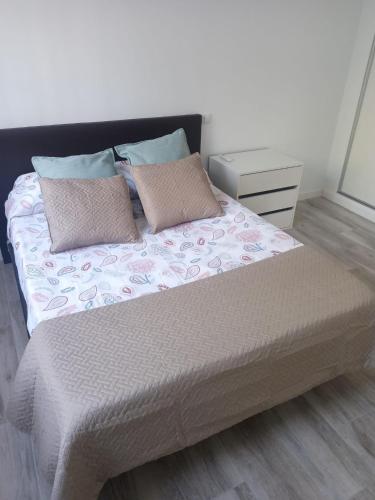 a bed with two pillows and a night stand at APARTAMENTO BAJO ALCOBENDAS in Alcobendas