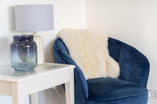a blue chair next to a white table with a vase at Stunning Views Over Mounts Bay with Balcony in Penzance