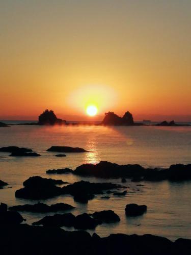 a sunset over the ocean with rocks in the water at はこにわ｜田舎暮らしが体験できる宿 in Kushimoto
