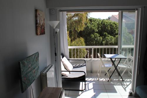 d'un balcon avec une chaise, une table et une fenêtre. dans l'établissement Studio l'Echappée mandréenne le calme entre mer et forêt, à Saint-Mandrier-sur-Mer
