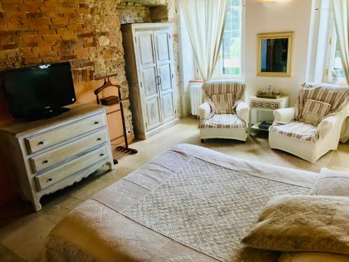 a bedroom with a bed and a tv and chairs at Domaine du Manoir in Les Avenières