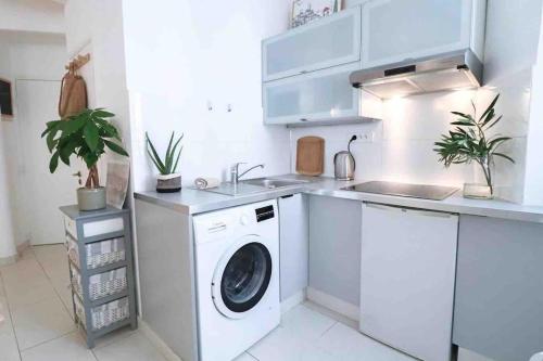 - une cuisine blanche avec un lave-linge et un évier dans l'établissement Cosy studio situé en plein cœur du vieil antibes., à Antibes