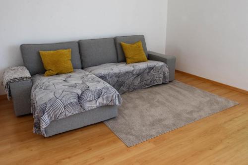 - un canapé gris avec 2 oreillers jaunes et un tapis dans l'établissement Grand T2 F2 Mulhouse Downtown FREE PARKING, à Mulhouse