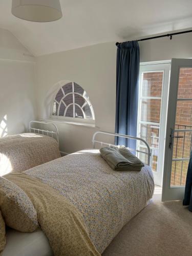 a bedroom with two beds and a window at The Barn in Saxmundham