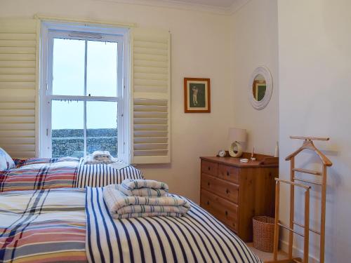two beds in a bedroom with a window and a dresser at Nautilus Cottage in Cellardyke