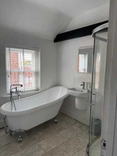 a white bathroom with a tub and a sink at The Barn in Saxmundham