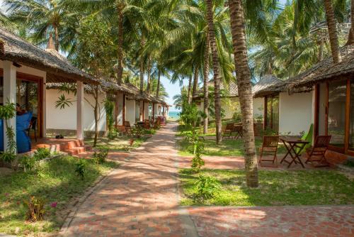 a row of cottages on the beach with palm trees at Ananda Resort in Mui Ne