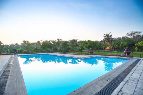 una piscina con acqua blu e alberi sullo sfondo di Kaveri Resort Sigiriya a Sigiriya