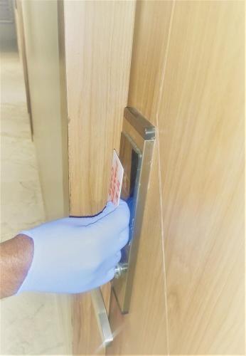 a hand in a blue glove unlocking a door at Hotel Akruti, Nanded in Nānded