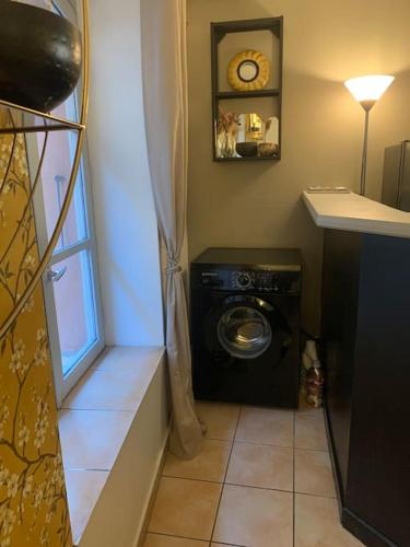 une buanderie avec une machine à laver et une fenêtre dans l'établissement Appartement chic & cosy, cœur de ville Perpignan, à Perpignan