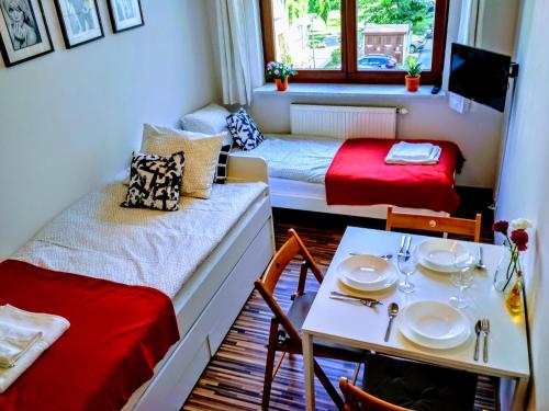ワルシャワにあるVitalia Apart Rooms Bobrowieckaのベッド2台、テーブル、ダイニングルームが備わる小さな客室です。