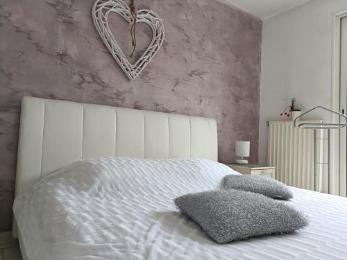 Un dormitorio con una cama blanca con una pared cardiaca en Virtuel Spa en Achicourt